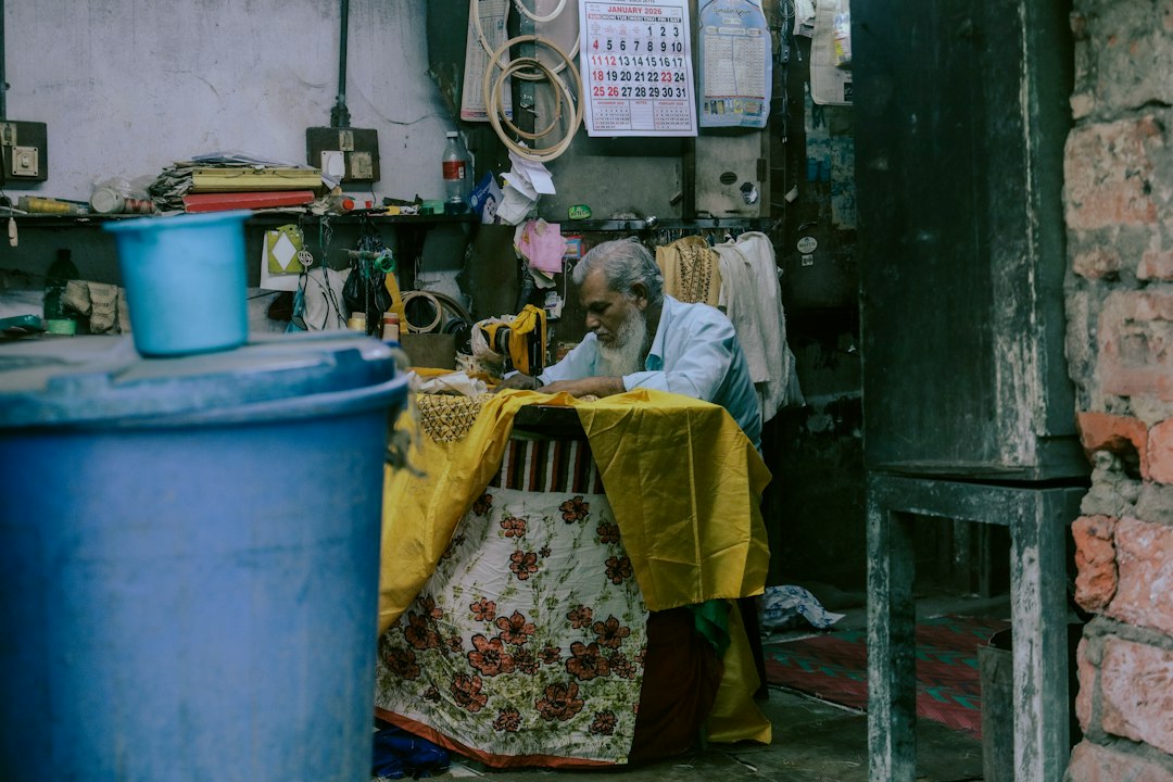 Experienced tailor carefully stitching fabric at his workstation.